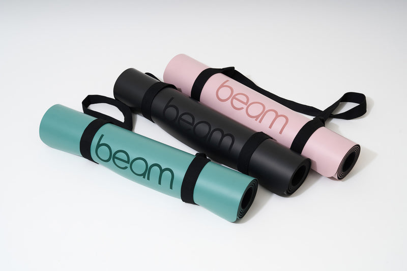 3 mats de yoga enrollados de diferentes colores.